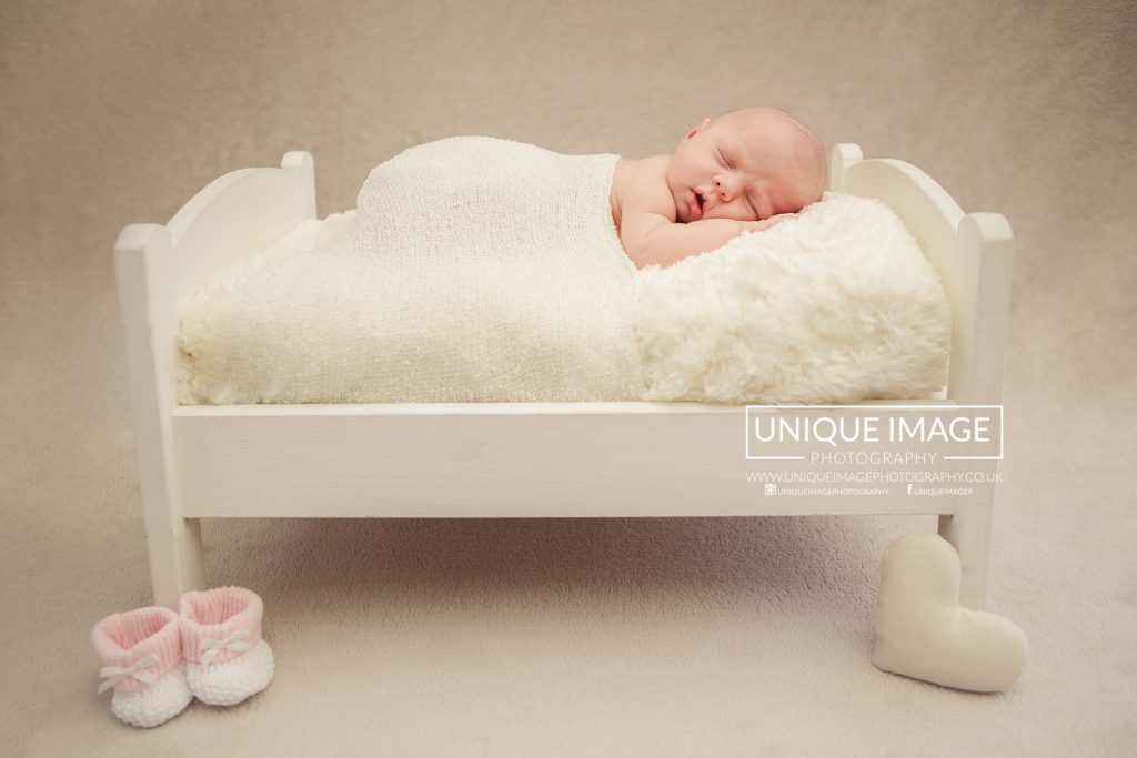 newborn girl in a little dolly bed